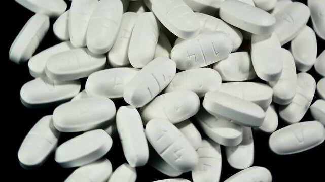 An Overhead view of a pile of white prescription pills turning counterclockwise under the camera.