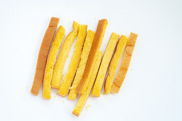 A pile of long, yellow, crunchy toast sticks is scattered on a clean white background.