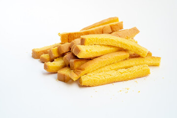 A small, messy pile of golden-yellow, crunchy breadsticks or rusk sticks lies on a clean white background.