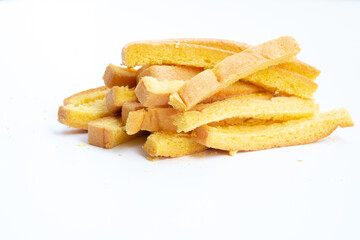 A small, messy pile of golden-yellow, crunchy breadsticks or rusk sticks lies on a clean white background.