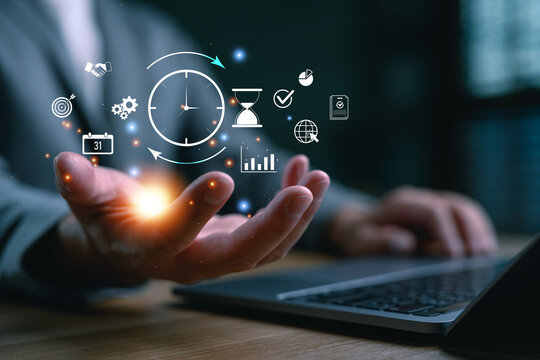 Businessman using time management tools and productivity icons on virtual screen to improve efficiency, planning and workflow optimization in modern digital workspace. Project manager concept.
