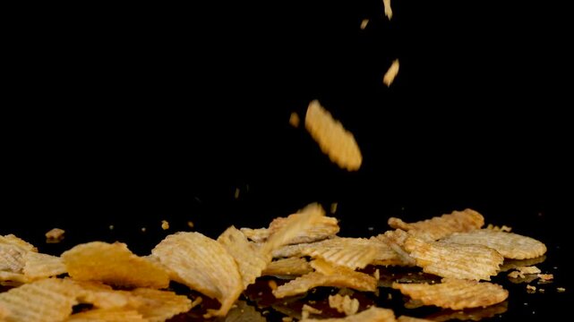 Potato Chips Dropping Onto Black Reflective Surface in Slow Motion