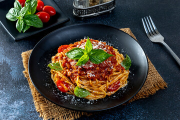 Pasta spaghetti bolognese with minced beef sauce, tomatoes, parmesan cheese and fresh basil in a plate