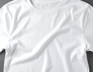 A simple, white, short-sleeved t-shirt lies folded on a grey background, showcasing its soft texture and subtle wrinkles