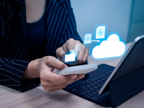 Businesswoman using smartphone and tablet to upload documents to cloud storage, concept of cloud technology, secure data transfer, file sharing and digital workflow management for remote work.