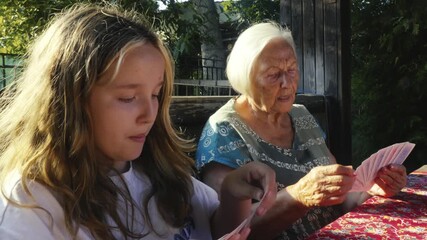 Children playing happy family card game with Grandma in summer garden - Powered by Adobe
