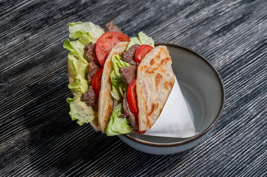 Homemade flatbread with beef and tomatoes on a table in a cafe. 