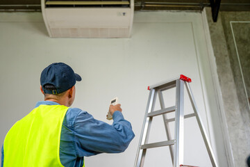 Air Conditioning Technician at Work: A dedicated technician, meticulously examines the indoor unit, skillfully using tools, embodies precision and expertise in the realm of climate control.