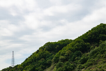 overcast sky and green hill with a electricity pylon