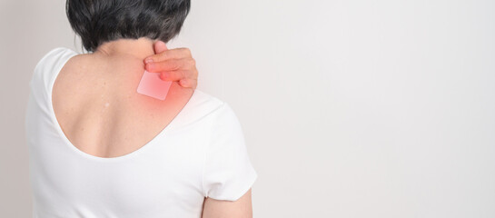Elderly Woman having Shoulder Pain with Medicated pain relief patch plaster for Muscle Inflammation...