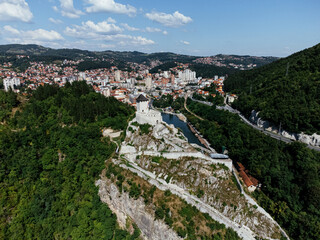 Obraz premium Aerial view of Uzice city in western Serbia with river, modern buildings, and surrounding green hills. g.