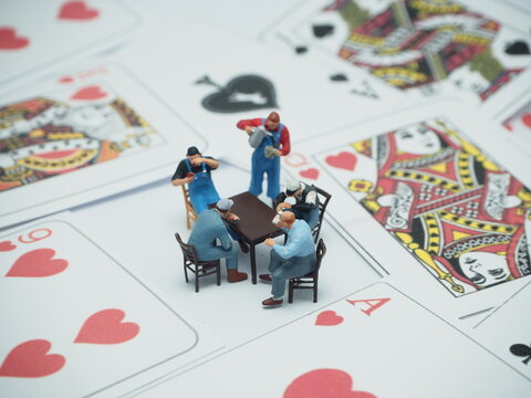 Mini toy of action figure at table with blurred background. Miniature photography concept design. Playing card with friend.
