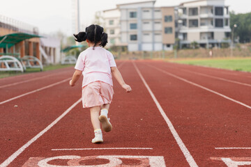 Fototapeta premium Young Girl Running on Athletic Track in School Playground During Evening, Inspiring Joy and Energy in Sporty Environment