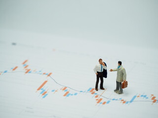 Fototapeta premium Mini toy of action figure at outdoor with blurred background. Miniature photography concept design. Minifigure of businessman character with market graph.