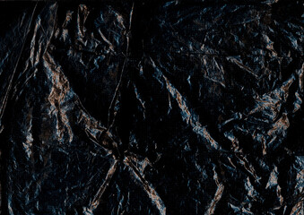 Old sheet. Wrinkled black paper. Crumpled rough plastic grunge blank abstract background. Dark distressed flare blur aged texture.