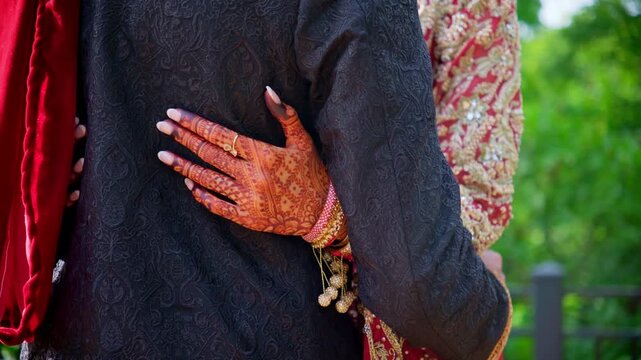Couple holding his hand. Traditional henna painted bridal hand. Red color is the Indian clothes, Elements of hindu wedding. 