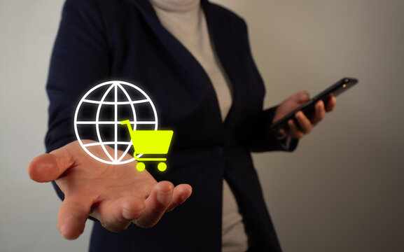Businesswoman holding a cell phone with her other hand holding a floating icon of a globe and a shopping cart, online shopping concept