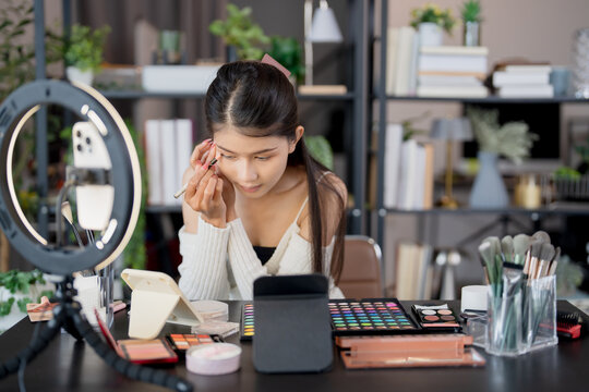 Asia woman beauty influencer makeup artist vlogger live streaming makeup tutorial on smartphone for social media - Powered by Adobe