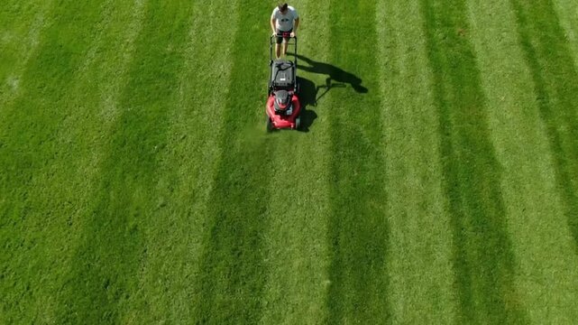 An aerial drone shot of a lawnmower creating perfect, satisfying stripes on a lush green lawn, a concept for lawn care and suburban life.