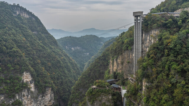 A zipline over the gorge. Silhouettes of people on tightropes. High lift. Green vegetation on the mountain slopes. Clouds in the sky. China. Wulingyuan. Grand Canyon