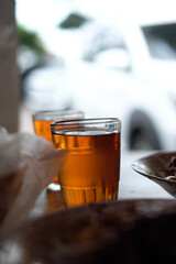 Two glasses of tea on a rustic table in a traditional Indonesian warung, capturing a quiet moment of local dining with natural light and cultural warmth.