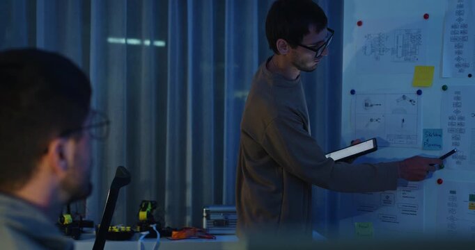 Team adult male engineer develop present AI robotics hand project at tech workspace night. Artificial intelligence, collaboration support prototype development, robotic, machine learn, training.