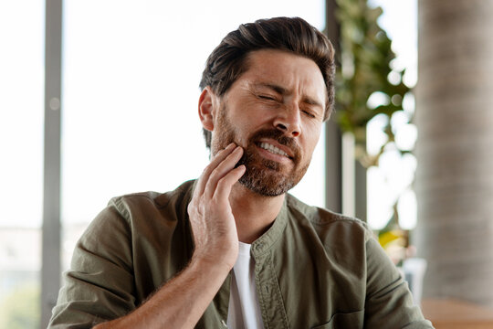 Man suffering from strong toothache touching his cheek
