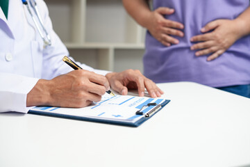 A male Asian doctor checks on an obese female patient at a desk, addressing her high blood...