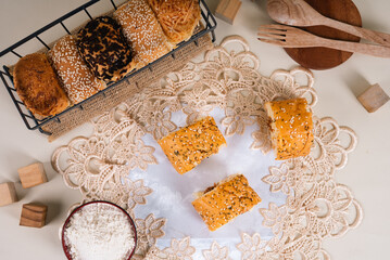 A basket filled with assorted bread rolls topped with sesame seeds, cheese, and chocolate...