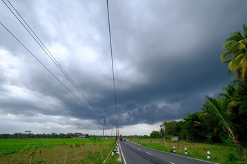 Cumulonimbus clouds are towering vertical clouds that are very tall, dense, and involved in thunderstorms and other cold weather. Cumulus and Nimbus cloud in countryside. Rural area. Asphalt road.
