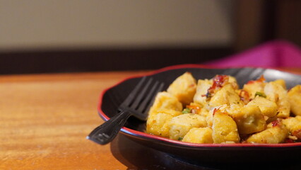 Close-up of spicy fried tofu with chili and garlic served on a black plate. Popular Asian vegetarian dish with crispy texture and savory flavor.