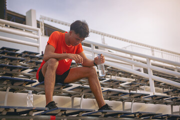 Tired runner with a bottle of electrolyte drink freshness after training outdoor workout at the...
