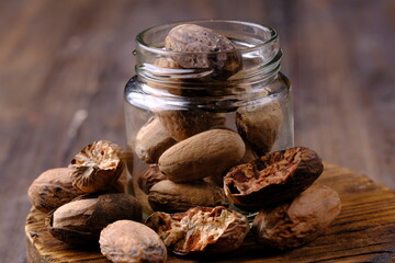 nutmeg in a glass jar on a teak cutting board. spice. Myristica fragrans.