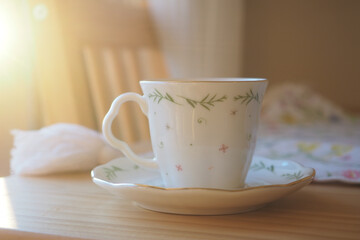 Delicate tea cup on wooden table in soft morning light