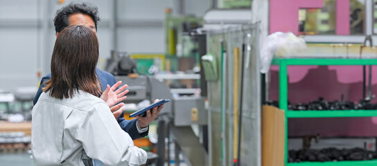 A male businessman and a female worker inspecting a factory