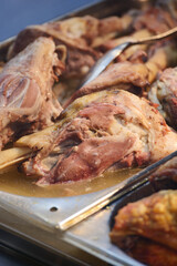 Cooking meats in a large metal tray at an outdoor market