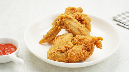 Crispy fried chicken wings served with chilli sauce on white plate
