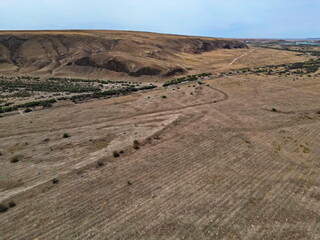 A rolling rocky valley with sand and rocks. The view from the drone.