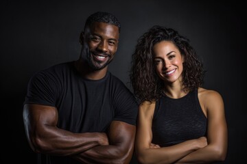 Obraz premium A confident athletic couple standing side by side with crossed arms. They are smiling at the camera, embodying strength, partnership, and a healthy lifestyle.