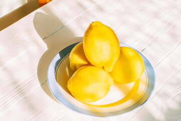 Fresh lemons on a sunlit plate in bright kitchen setting