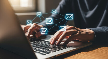 Person's hands type on laptop keyboard with glowing envelope icons connecting for communication