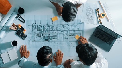 Top down aerial view of interior designer writing at sticky note while planning design with engineer team. Group of diverse architect and skilled manager looking building construction. Alimentation.