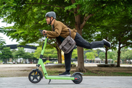 Young Asian man ride scooter EV eco friendly transport. Sustainable save energy lifestyle. Commute and carbon neutral transportation. Asian tourist man put on helmet ride the scooter EV