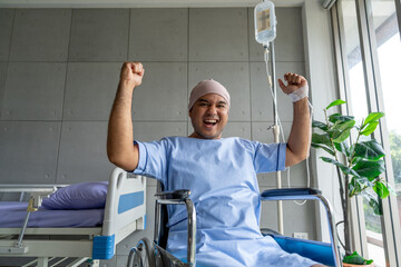 A male cancer patient in a wheelchair with an IV smiles with joy and hope showing strength and positivity during treatment. Man receiving IV therapy in a wheelchair appears happy and uplifted