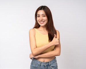 Fototapeta premium Beautiful smiling happy young asian woman in yellow shirt showing thumbs up. Charming female lady standing pose on isolated white background. Asian woman people looking camera confident