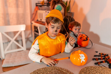 Children wearing halloween costumes preparing decorations at home