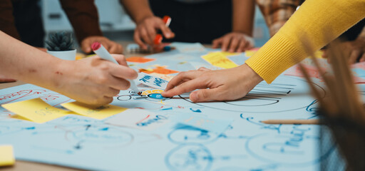 A vibrant brainstorming session featuring diverse hands working together on a large paper,...