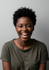 Happy young woman in a casual olive green t-shirt, laughing broadly against a neutral backdrop. Portrait of a joyful female student in a modern studio setting.