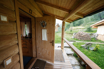 Rustic wooden porch with an open door overlooking a cozy rural landscape