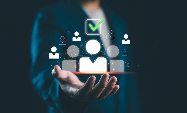 Human Resources Recruitment and Hiring Concept. Businessman holds virtual icons representing potential candidates, with one icon highlighted and a check mark, illustrating HR recruitment and hiring.